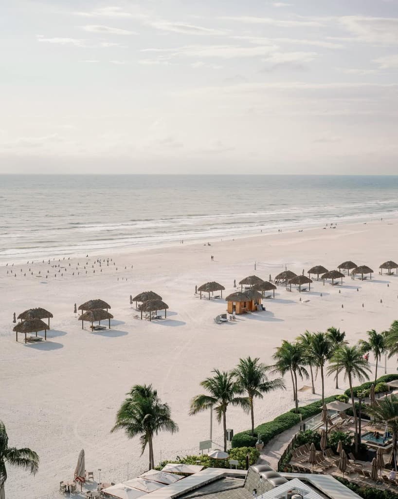 Aerial view of Marco Island beach with tiki huts and palms